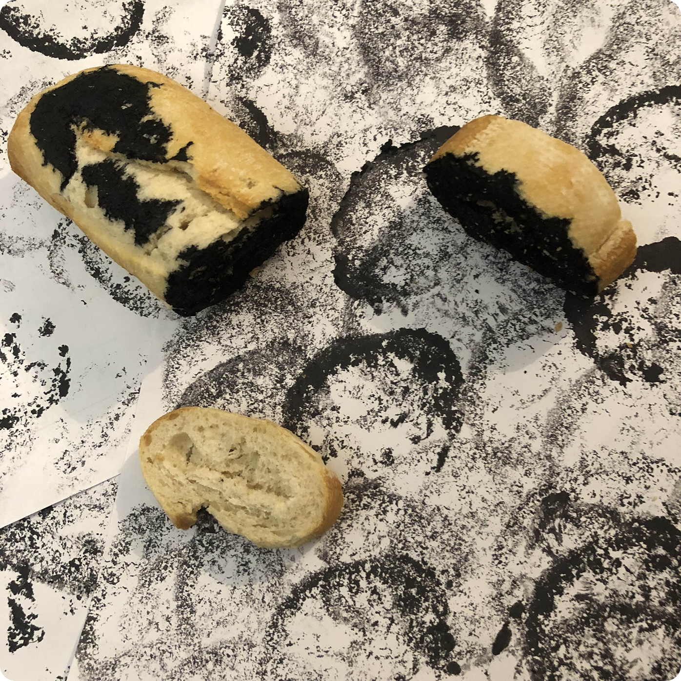 Ink-dipped bread on top of paper with stamps of the bread.
