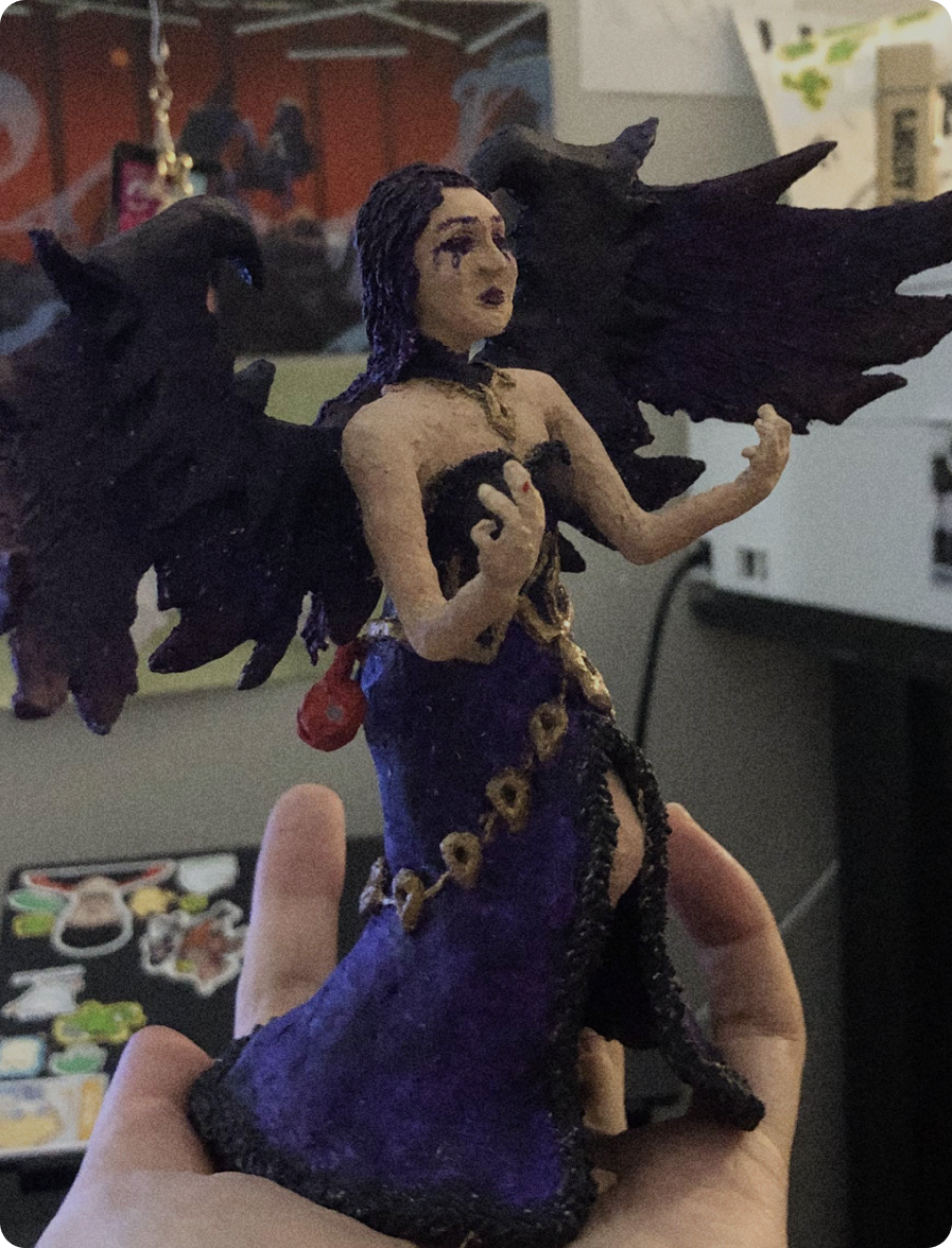 Hand holding a painted 3D-pen sculpture of Morgana with black wings and a purple dress.